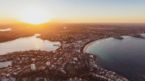 High angle view of river and buildings against sky during sunset