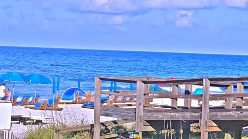 Chairs on beach against blue sky