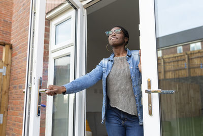 Smiling woman opening house doors