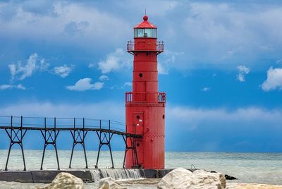 Lighthouse by sea against sky