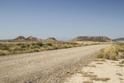 Road by desert against clear sky