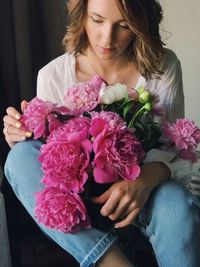 Midsection of woman holding pink flower