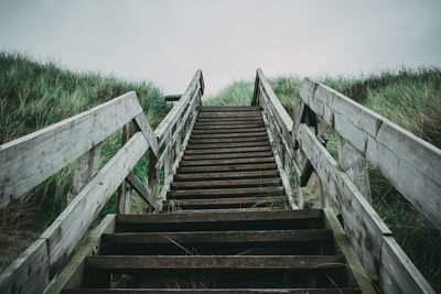 Wooden staircase on field against sky