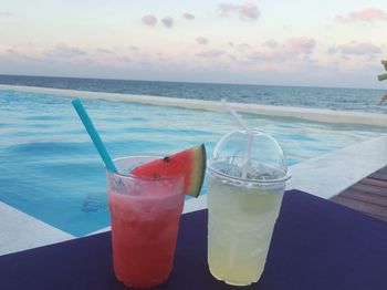 Close-up of drink on beach against sky