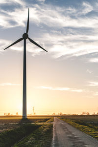 Low angle view of windmill on country road against sky
