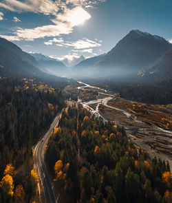 High angle aerial view of river and road running through forest and mountainous landscape