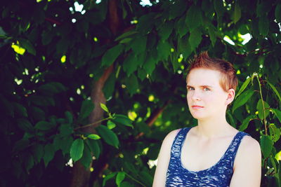 Portrait of young woman in front of tree