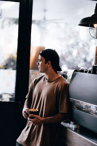 Man looking out the window while standing in coffee shop 