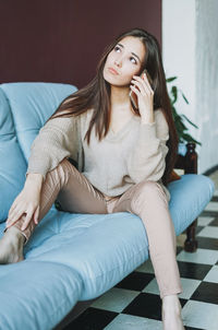 Young woman sitting on sofa at home