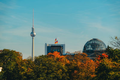 Communications tower in city against sky