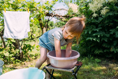 Little preschool girl helps with laundry. child washes clothes in garden