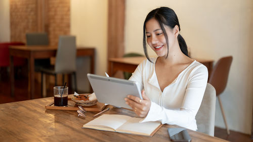 Young woman using mobile phone at table