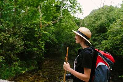 Side view of man looking at camera in forest