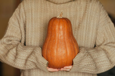  pumpkin in the hands in woolen warm oversize sweater, food lifestyle monochrome trend