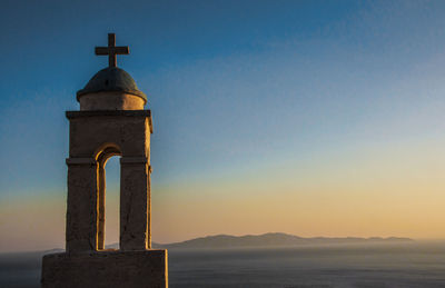 Spire with cross by mountains against