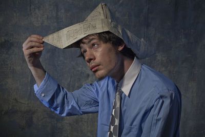 Portrait of a young man looking away against wall