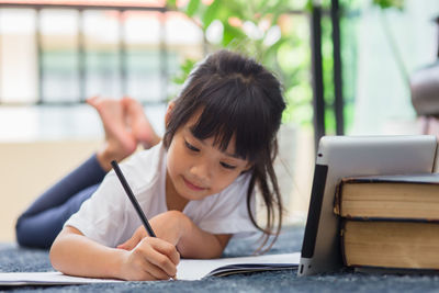 Portrait of boy holding book on table