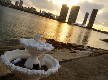 Statue by river in city against sky