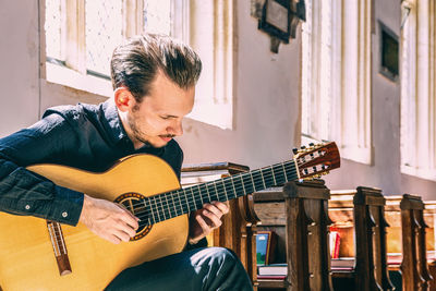 Man playing guitar while sitting at table