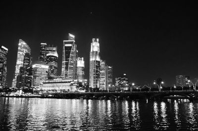Illuminated city skyline by river at night