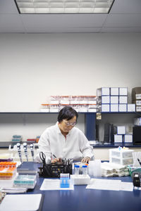 Senior female scientist using machinery in laboratory