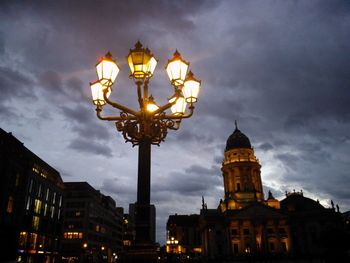 Low angle view of illuminated street light against cloudy sky