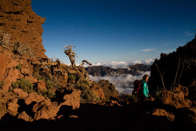 Woman standing on mountain against sky