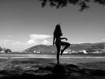 Woman standing at beach against sky