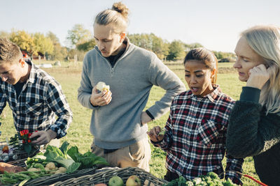 Multi-ethnic male and female friends selling organic vegetable at farmer's market