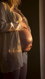 Midsection of woman standing against black background