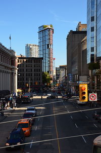 Cars on city street by buildings against sky