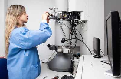 Female scientist loading a specimen using a sample holder into a transmission electron microscope