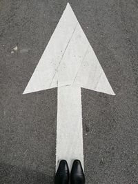 High angle view of shoes by arrow symbol on road