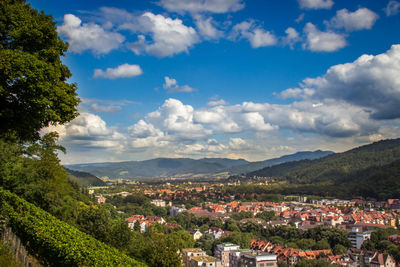 High angle view of residential district by mountains against cloudy sky