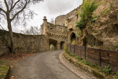 Road leading towards old ruin building against sky