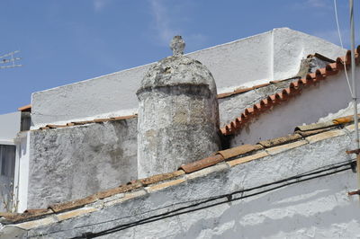 Low angle view of chimney on roofs against sky