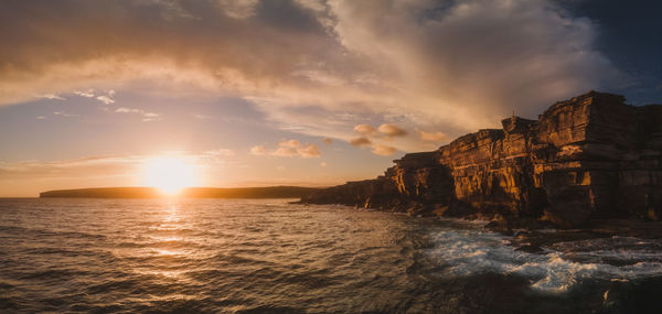 Drone panorama of sheer coastal cliff shoreline during  sunset with dramatic cloud formation