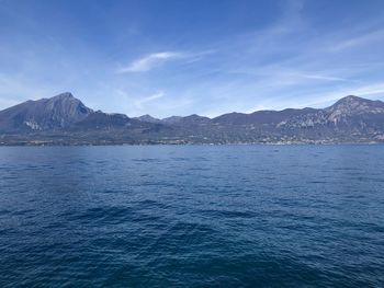 Scenic view of sea and mountains against blue sky