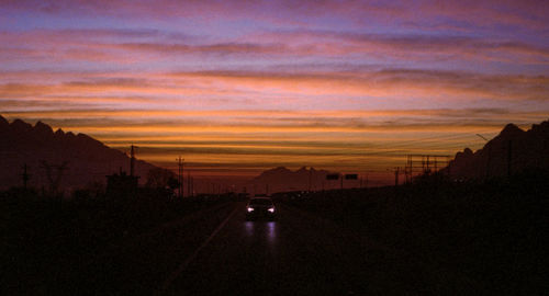 Silhouette road against sky during sunset