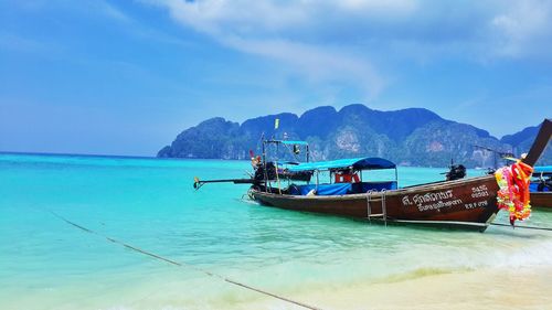 Longtail boats moored at beach against sky