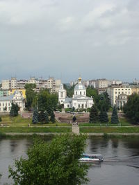 Buildings at waterfront against cloudy sky