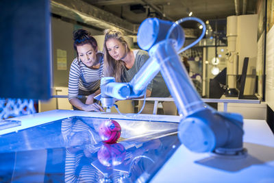 Tech developers looking at automated robotic arm at workshop