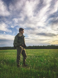 Side view of man standing on field against sky