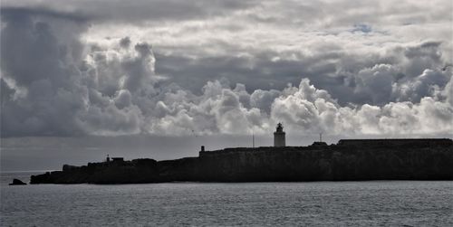 Lighthouse by sea against sky