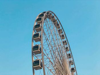 Low angle view of ferris wheel against clear blue sky