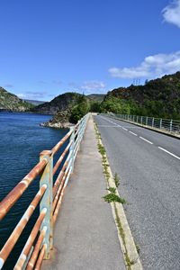 Empty road by sea against sky