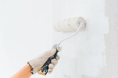 Close-up of hand holding umbrella against white wall