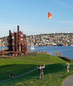 People playing on field by sea against clear sky