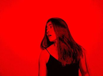 Portrait of young woman against red background
