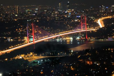 High angle view of illuminated bridge along cityscape at night